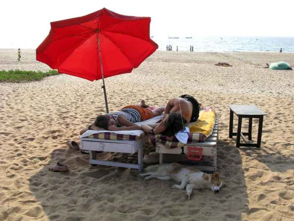 Menschen und Hund am Strand von Goa